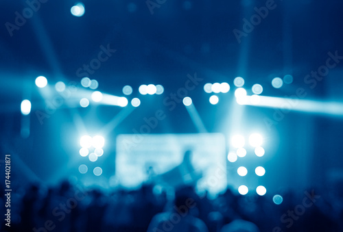Blurred blue background of a vibrant concert or event with bright bokeh lights and spotlights illuminating a crowd. Abstract party atmosphere, perfect for overlays, backgrounds, or creative designs.