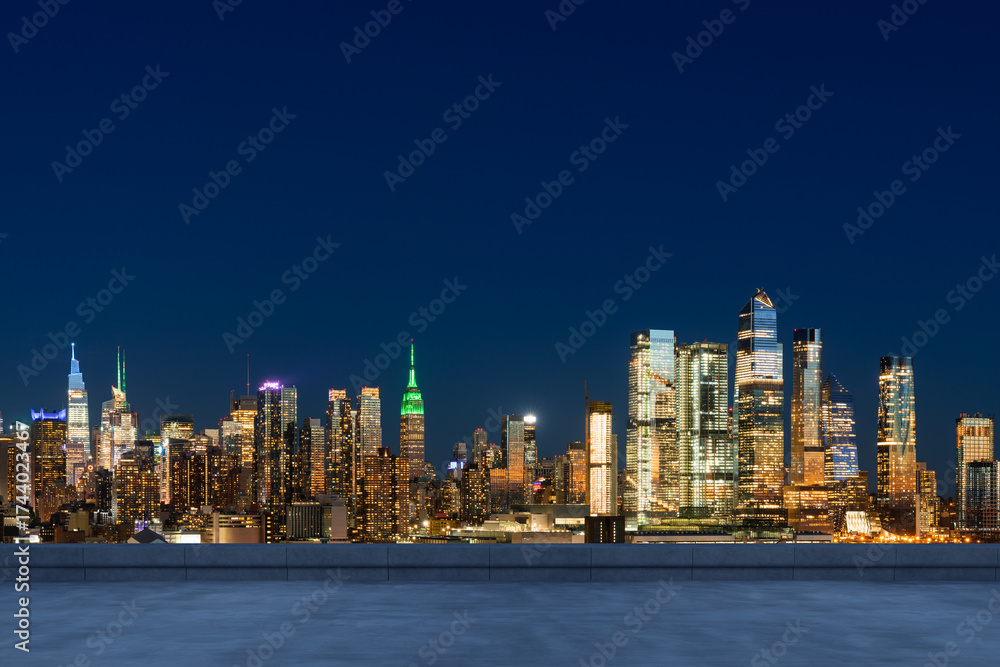 Fototapeta premium Rooftop view of illuminated Manhattan skyline at night with modern skyscrapers and iconic Empire State Building under dark blue sky in New York City, USA.
