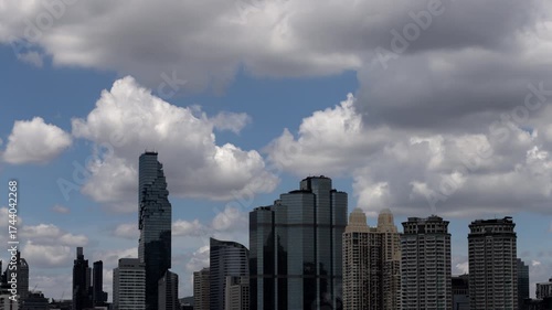 A time-lapse captures clouds drifting gracefully over Bangkok skyscrapers under a clear blue sky