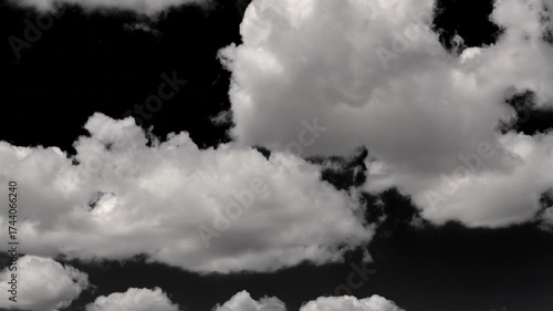 White clouds move rapidly across a black sky, captured in smooth motion.