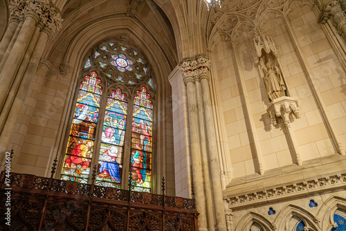 Photography This image showcases a colorful stained-glass window depicting biblical scenes, set within a Gothic arched frame