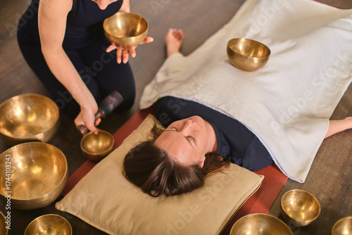 Singing bowl therapy with relaxed woman on floor
