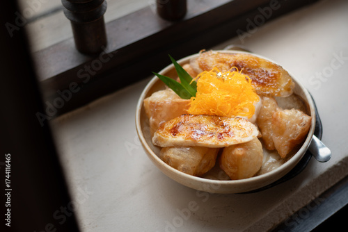 Crispy Thai Roti Fusion: Golden, flaky roti puffs paired with caramelized banana slices and topped with a nest of sweet, shimmering Foi Thong (golden egg yolk threads). A delightful texture.