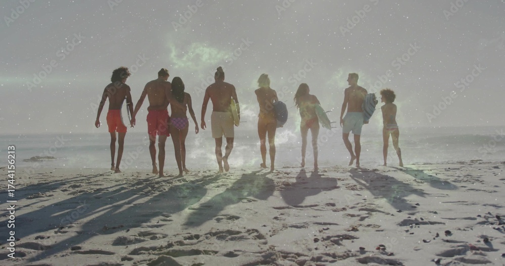 Fototapeta premium Walking group of eight surfers in swimwear carrying surfboards toward ocean at beach, wet sand
