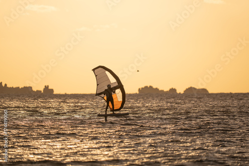 Wingfoiling in Brittany at sunset, a few rocks in the background