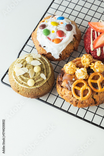 Assortment of fresh chocolate American chip cookies with salted camel, caramel popcorn, matcha tea , marshmallow and colorful candies on white background. Flat lay of different cookies on cooling rack