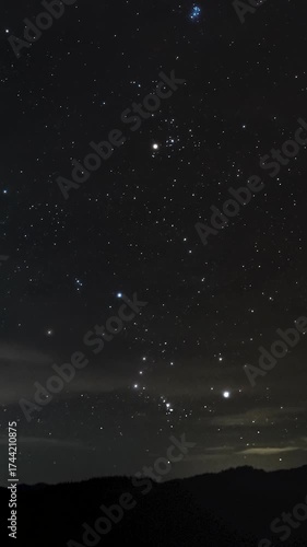 Starry night sky over mountain horizon, Bright constellations sparkle above dark mountains under the clear night sky, time lapse, vertical footage