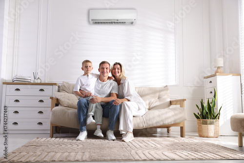 Happy family enjoying comfortable temperature in room with air conditioner