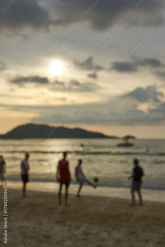 Fototapeta premium Silhouettes of young males playing soccer on beach at sunset.
