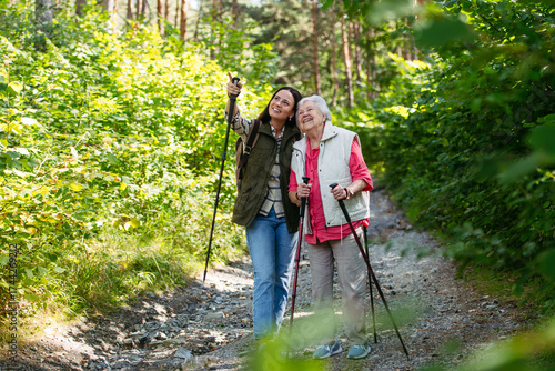 Senior woman and daughter enjoying hike with trekking poles.