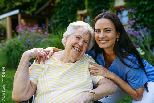 Portrait of caregiver taking care of elderly woman in wheelchair.