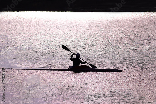 A rower in a kayak floats on the river...  A  silhouette