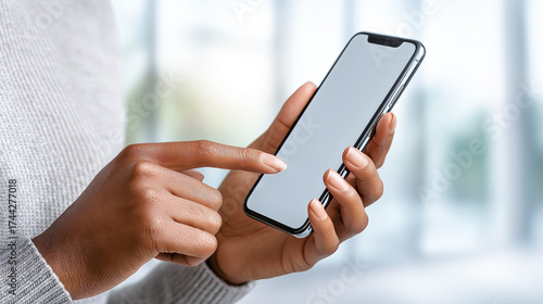 Close-up of a woman using a smartphone with a blank white screen. Blurred background and copy space for text or design.