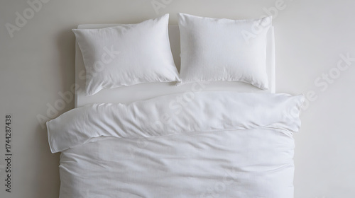 A neatly made bed with crisp, white linen conveys a sense of calm and comfort. Pillows are plumped, and the duvet is smooth, creating an inviting resting place.
