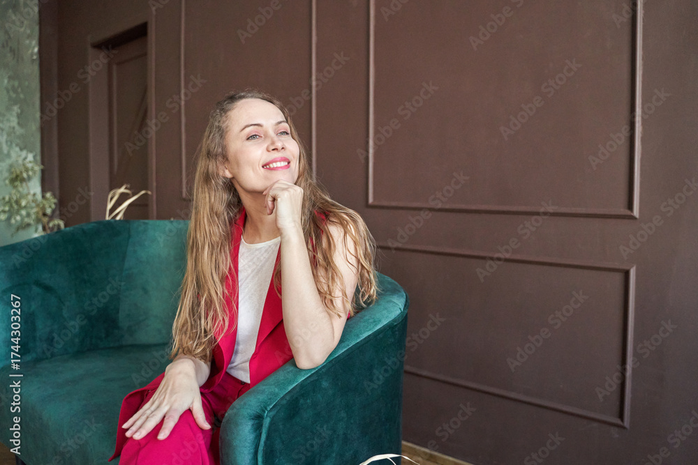 Obraz premium Smiling caucasian young female relaxing on green sofa in stylish room with brown walls.