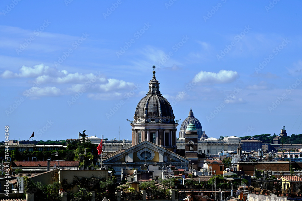 Fototapeta premium Rome, Italy areal view of rooftops viewed from the top of Spanish Steps. church cupolas and clay residential roofs. blue sky background. white clouds. travel and tourism concept. St. Peter's Basilica