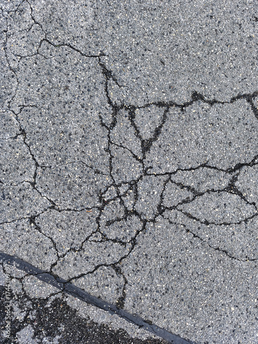 Close up of weathered asphalt pavement with severe spider web cracks texture