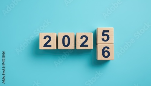Wooden cubes with changing numbers from 2025 to 2026 on blue background, new year transition and future concept