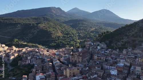 Aerial drone view of Collesano Sicilian mountain town at sunset with Basilica San Pietro church and historic stone streets in the Madonie Mountains, Sicily, Italy. Old mountain town in Sicily