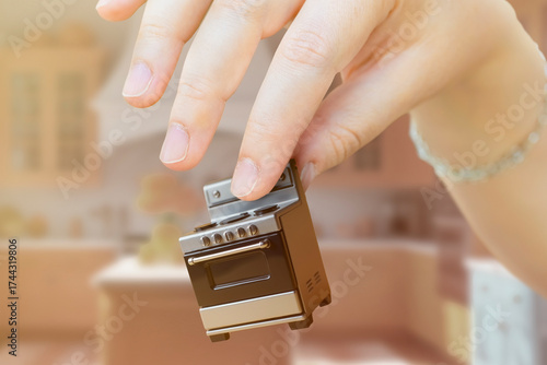 Close-up of a toy stove in a person's hand. Concept of compact home appliances for a small apartment.