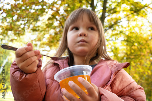 Close-up of a child holding a dessert with a fork in the park. Quick snack.