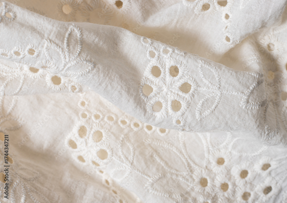 Obraz premium close-up of a white cotton fabric with delicate floral embroidery and cutwork details, material with soft texture and elegant handcrafted appearance