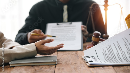 Lawyer discussing legal contract with client in office, providing advice and consultation. Scales of justice and gavel on desk