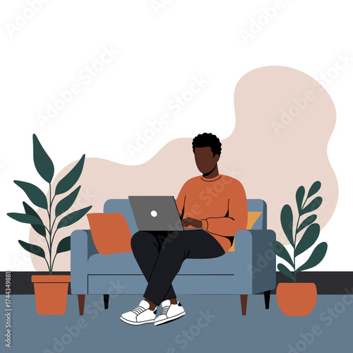 Young Black man uses laptop on sofa at home Remote work online learning relaxed lifestyle