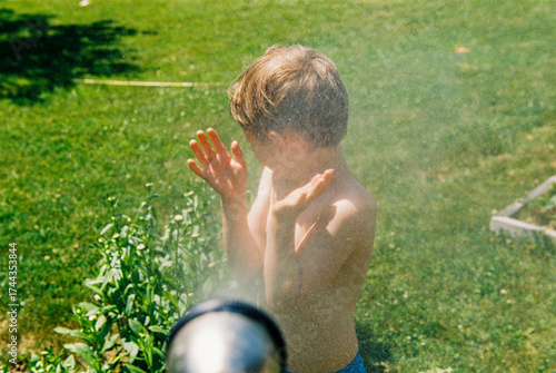 Child is sprayed by hose in backyard