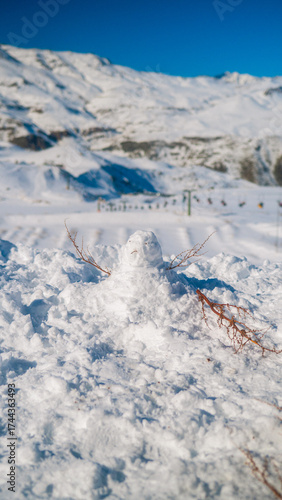 Small snowman with tree branch arms in Farellones Park, Chile, with snowy landscape and Andes Mountains in the background