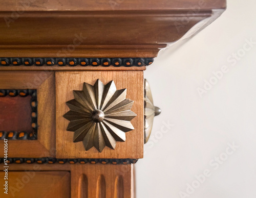 Wooden carved furniture detail with metallic flower ornament