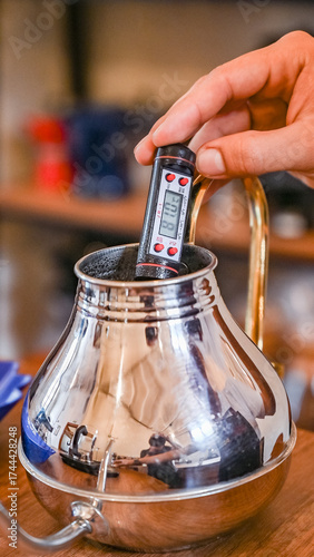 Hand measuring coffee water temperature with digital thermometer
