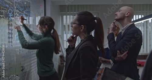 Business team analyzes data on a transparent whiteboard during a strategic planning meeting to enhance and optimize their work.