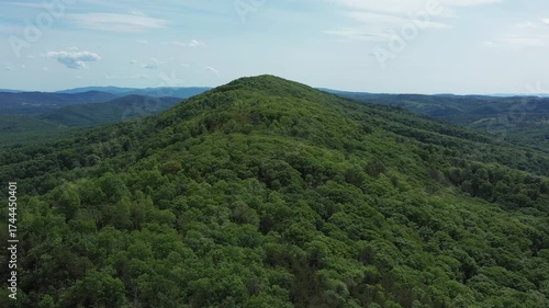 Aerial footage of Big Ridge Mountain in Lost River State Park, West Virginia, as the camera glides forward and ascends, revealing rolling forested peaks under a bright summer sky.