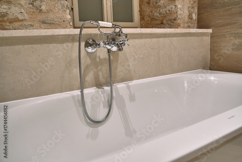 A Serene Bathtub Scene Highlighting Elegant Bathroom Fixtures and Natural Stone Walls for a Relaxing Home Spa Experience