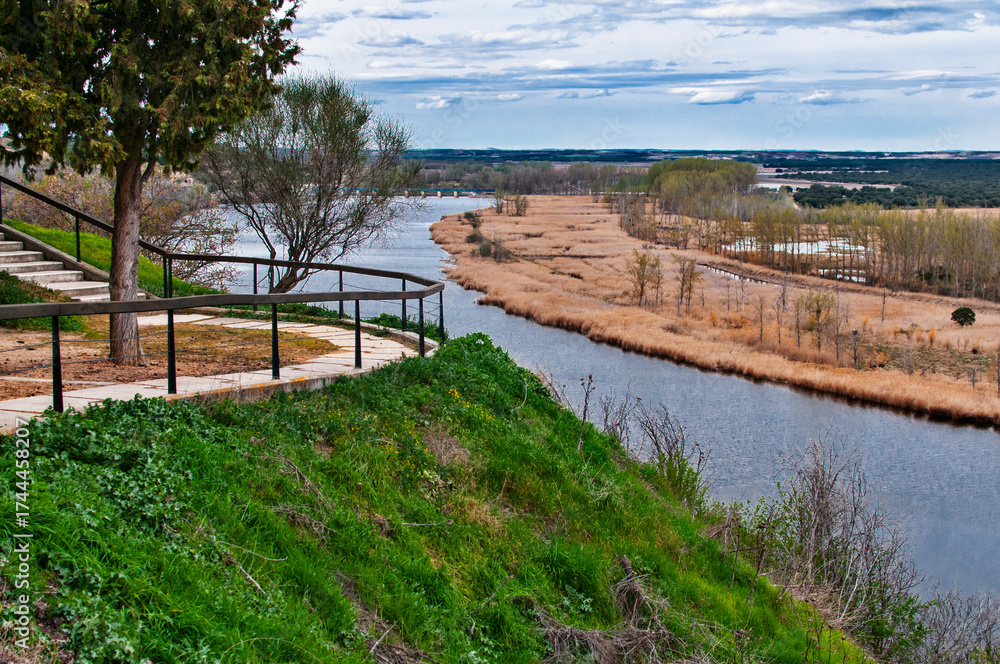 Fototapeta premium River winding through marshland with path on hillside
