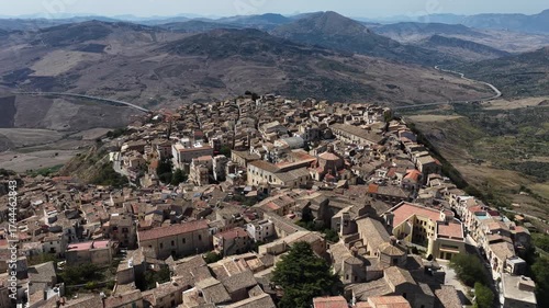 Aerial drone view of Polizzi Generosa, a picturesque Sicilian mountain town perched on rocky cliffs showcasing traditional stone buildings and panoramic views of the Madonie Mountains, Sicily, Italy