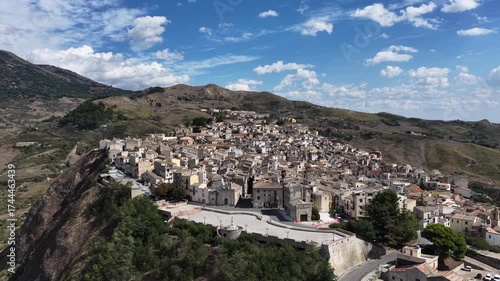 Aerial drone view of Polizzi Generosa, a picturesque Sicilian mountain town perched on rocky cliffs showcasing traditional stone buildings and panoramic views of the Madonie Mountains, Sicily, Italy
