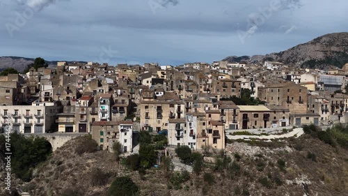 Aerial drone view of Polizzi Generosa, a picturesque Sicilian mountain town perched on rocky cliffs showcasing traditional stone buildings and panoramic views of the Madonie Mountains, Sicily, Italy