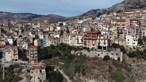 Aerial drone view of Polizzi Generosa, a picturesque Sicilian mountain town perched on rocky cliffs showcasing traditional stone buildings and panoramic views of the Madonie Mountains, Sicily, Italy