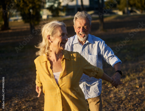 Fotografie Happy active senior couple having fun in park outdoors