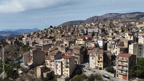 Aerial drone view of Polizzi Generosa, a picturesque Sicilian mountain town perched on rocky cliffs showcasing traditional stone buildings and panoramic views of the Madonie Mountains, Sicily, Italy