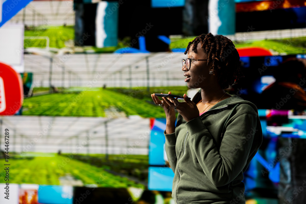 Fototapeta premium Mesmerized woman holding smartphone celebrating freedom of unlimited video content in metaverse. Person using mobile phone to look at online video channels, isolated over giant digital wall backdrop