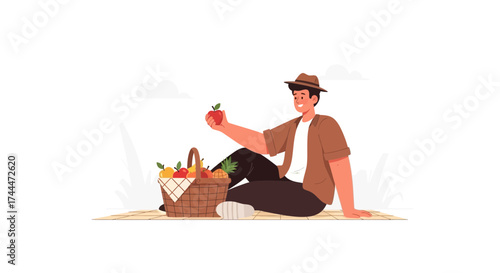 A man relaxing at a picnic with an apple and a fruit basket smiling peacefully