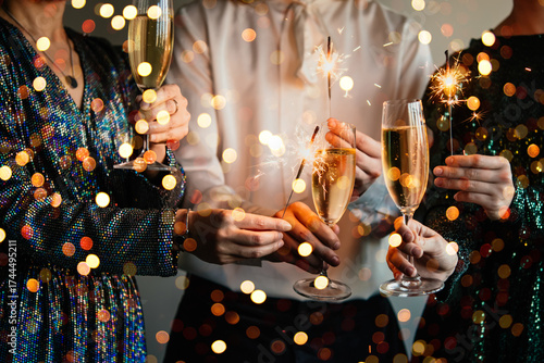 Friends celebrating Christmas or New Year eve party with Bengal lights and champagne.