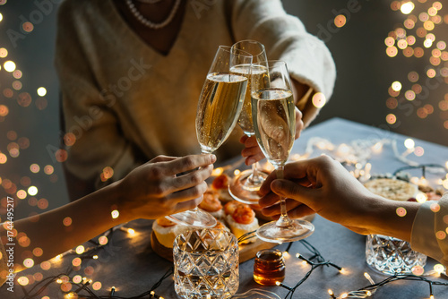 Friends celebrating Christmas or New Year eve party with champagne or sparkling wine.
