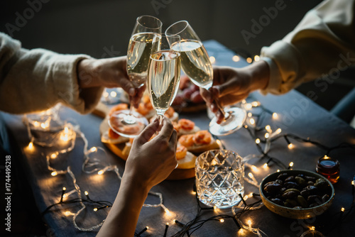 Friends celebrating Christmas or New Year eve party with champagne or sparkling wine.