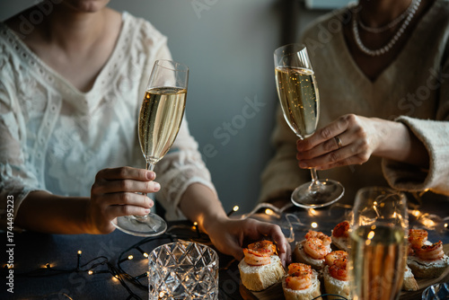 Friends celebrating Christmas or New Year eve party with champagne or sparkling wine.