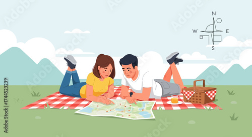 Couple Planning Trip on Picnic Blanket Outdoors Examining Map with Compass and Picnic basket
