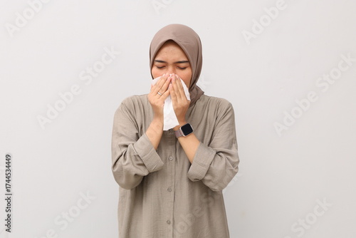 Pretty Asian muslim girl is Sneezing into a tissue because of her allergy or cold